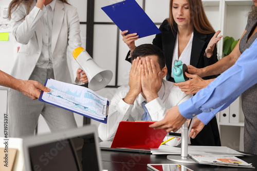Mature businessman suffering from noisy colleagues in office