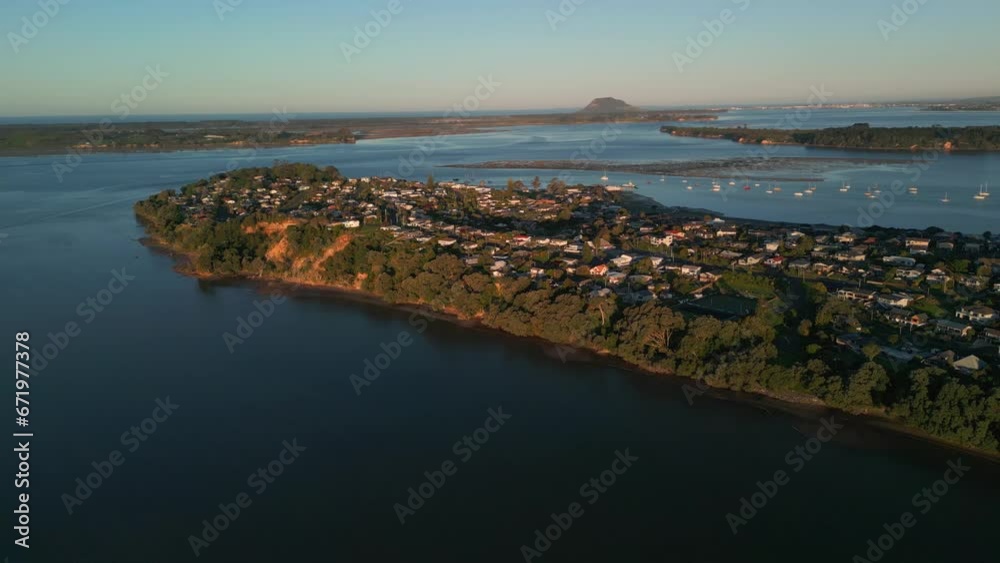 Sunset aerial view of coastal neighborhood in Akaroa, New Zealand, overlooking Mount Manganui Sunset aerial view of coastal neighborhood in Akaroa, New Zealand, overlooking Mount Manganui