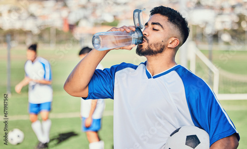Fototapeta Naklejka Na Ścianę i Meble -  Football, athlete and man drinking water outdoor on a sports field for fitness competition. Tired male soccer player on a break and exhausted from exercise, challenge or training workout for health