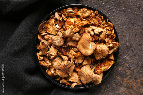 Plate with tasty dried mushrooms on dark background