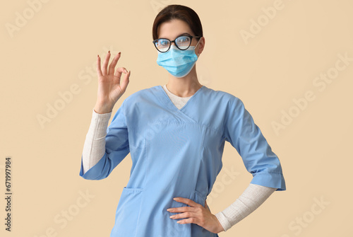 Healthcare professional showing ok sign, medical worker in face mask and scrubs