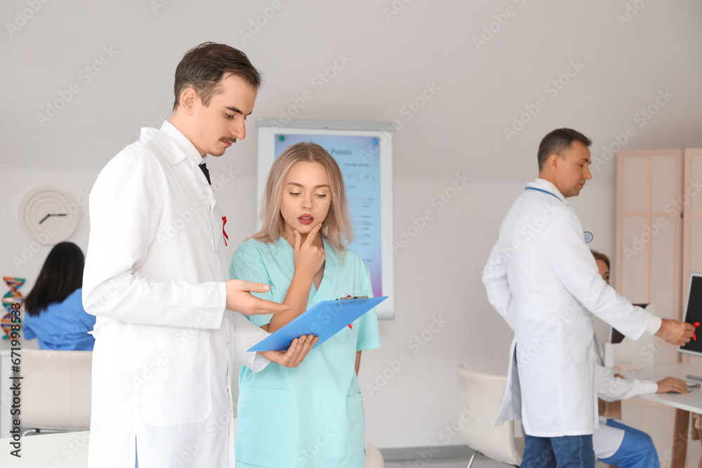 Professional doctors with red ribbons discussing something in clinic. World AIDS Day concept Professional doctors with red ribbons discussing something in clinic. World AIDS Day concept