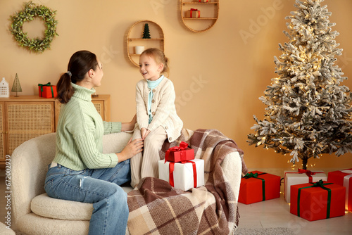 Young mother with her little daughter at home on Christmas eve