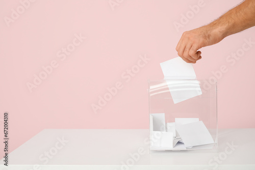 Voting man near ballot box on pink background