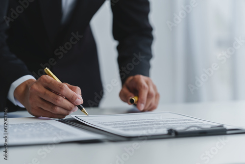 Businessman holding a pen to sign a contract, making a detailed agreement, business contract for finance, real estate, insurance, taxes and signing an official document. photo