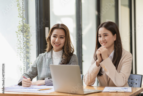 Professional and focused Asian businesswoman or auditor is discussing plans with clients, discussing presentation of new startup project idea. Analyze statistics and investment markets at the office.
