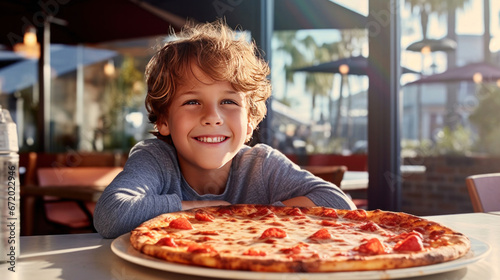 American happy boy sitting at table with tasty crunchy fresh pizza.