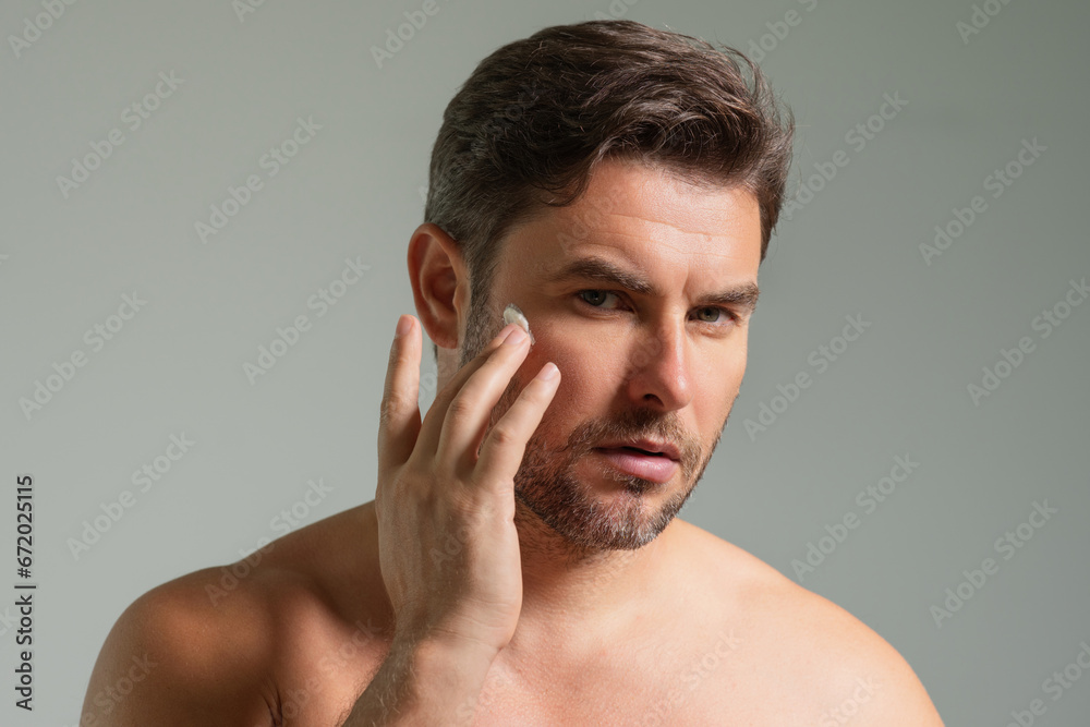 Obraz premium Aged care. Beauty man with cosmetic cream. Male spa model applying skin care cream product. Morning skincare cream, lifting and anti-aging wrinkle effect. Skin care. Man with perfect soft skin.