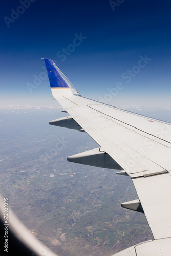 Beautiful view from the airplane window from above to the clouds  mountains  roads  rivers. Picturesque landscape from a helicopter window. Airplane wing in the window above the clouds on a sunny day.