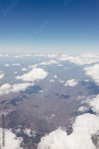 Beautiful view from the airplane window from above to the clouds, mountains, roads, rivers. Picturesque landscape from a helicopter window on a sunny day.