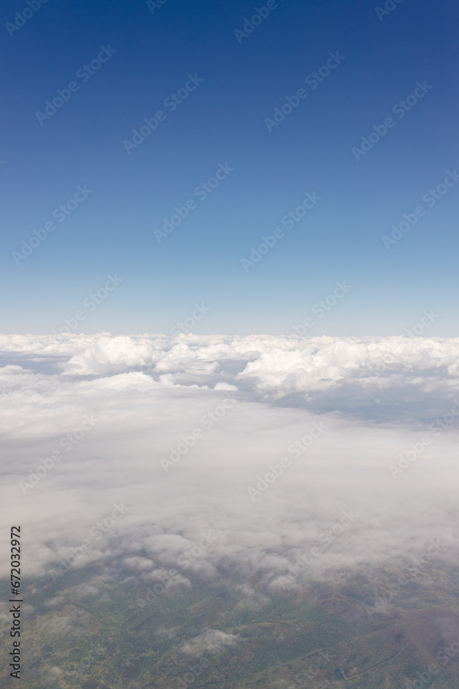 Beautiful view from the airplane window from above to the clouds, mountains, roads, rivers. Picturesque landscape from a helicopter window on a sunny day. Beautiful view from the airplane window from above to the clouds, mountains, roads, rivers. Picturesque landscape from a helicopter window on a sunny day.