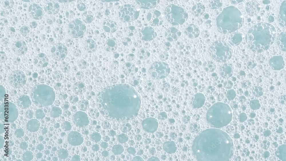 Bubbles of white soap foam on a blue background. Bathtup Soap Foam. Texture of Soap Foam Bubbles. Natural White Shampoo Bubbles Motion. High quality 4k footage
