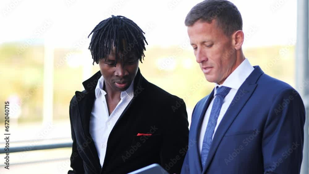 Black and White Colleagues Walking, Collaborating, and Discussing on Tablet