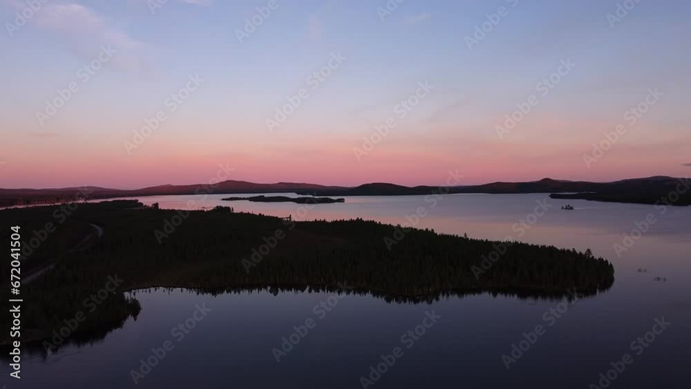 Picturesque evening dusk blue hour aerial over calm lake in Sweden. Orange blue sky with forest nature landscape silhouettes Picturesque evening dusk blue hour aerial over calm lake in Sweden. Orange blue sky with forest nature landscape silhouettes