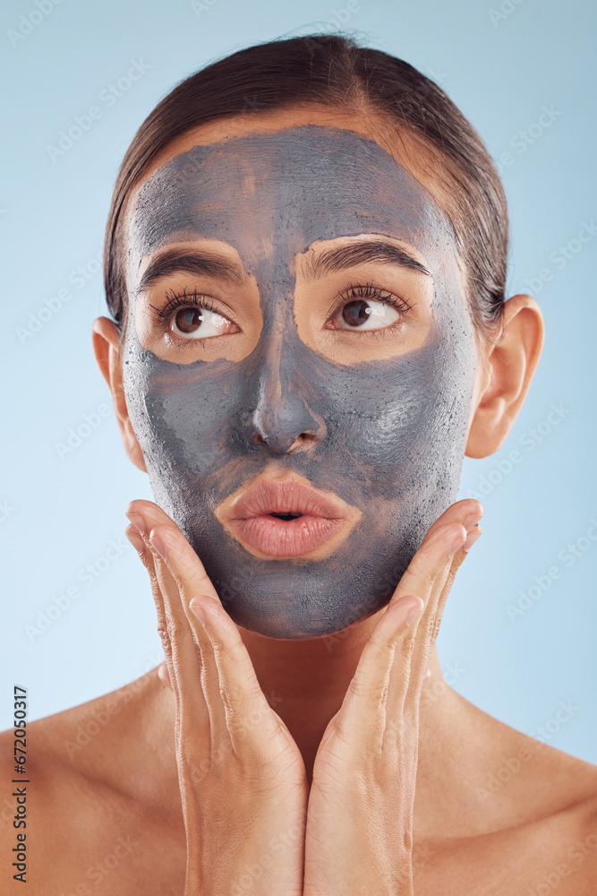 Fototapeta premium Face mask, skincare and beauty of woman with cosmetic facial treatment isolated in a blue studio background. Skin, charcoal and young female person with clean, hydration and dermatology cream