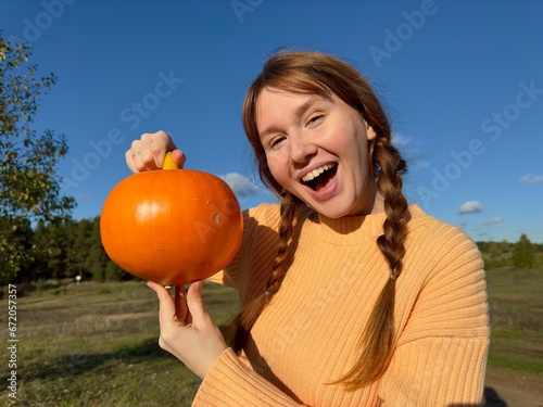 Happy young woman in nature, countryside with pumpkin, concept autumn, harvest, village, halloween photo