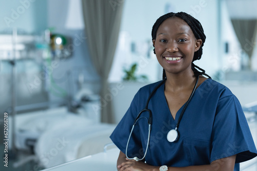 Portrait of happy african american female doctor wearing scrubs in hospital, copy space photo
