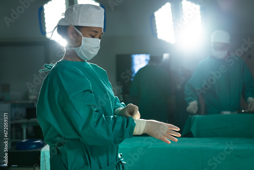 Asian female surgeon wearing medical gloves in operating theatre at hospital photo