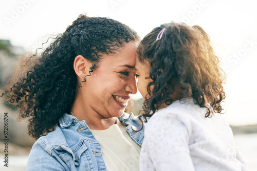 Beach, sunset and love of mom for girl, child or daughter together outdoor in nature on holiday, vacation or heads touching with a smile. Mother, black woman and kid with happiness, freedom or care