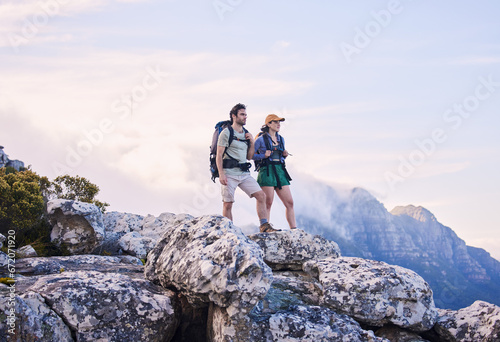 Mountain, hiking view and man with woman on peak for adventure in nature, landscape and travel. Outdoor trekking, couple on cliff and relax in scenic clouds for natural journey, walking and looking.