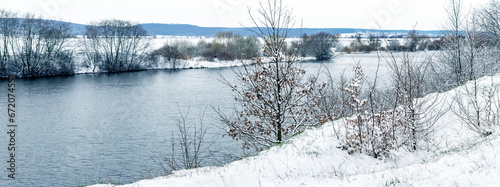 Winter landscape with snow-covered trees on the river bank, panorama © Volodymyr