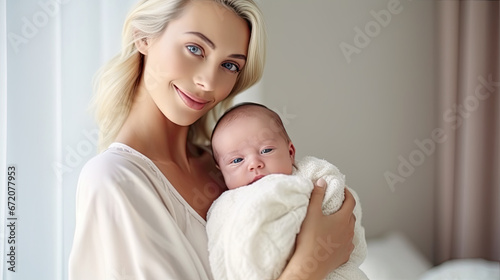 Pretty blonde american woman holding newborn baby in her arms