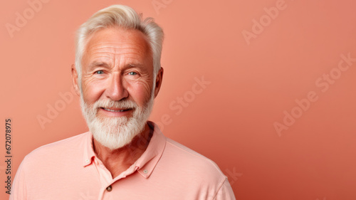 Chipper senior man with full white beard stands before a peach backdrop
