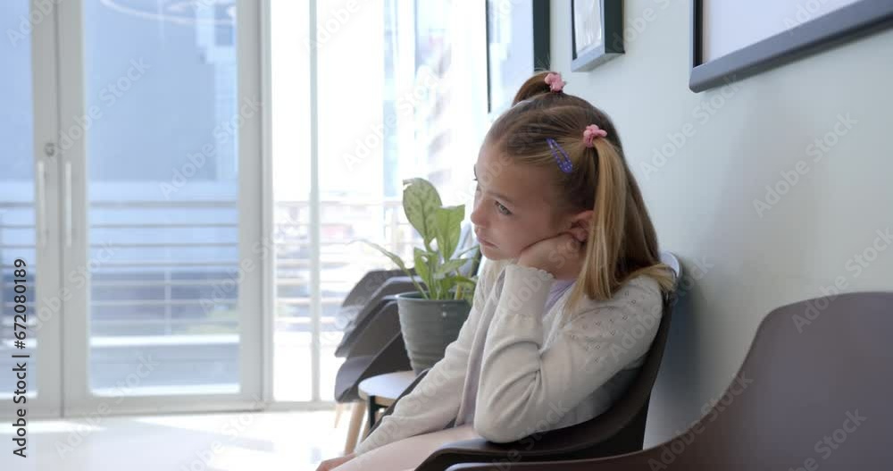 Bored caucasian girl patient sitting in hospital waiting room, copy space, slow motion Bored caucasian girl patient sitting in hospital waiting room, copy space, slow motion