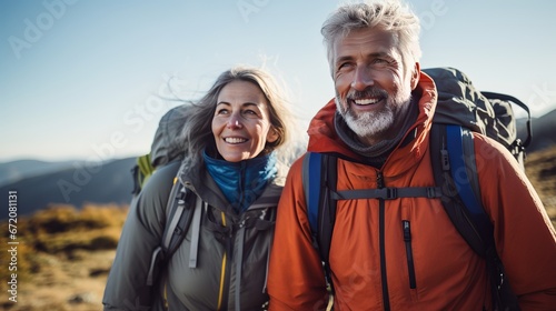 Dynamic senior caucasian couple climbing in mountains with rucksacks, getting a charge out of their experience photo