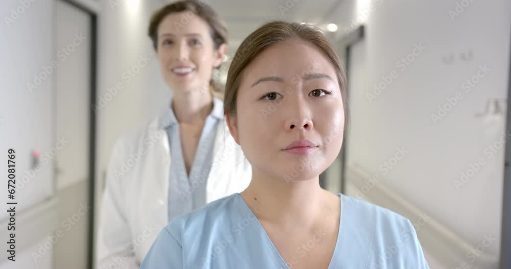 Portrait of happy diverse female doctors standing in hospital corridor, selective focus, slow motion