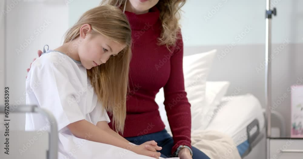 Happy caucasian mother comforting daughter patient sitting on hospital bed, copy space, slow motion Happy caucasian mother comforting daughter patient sitting on hospital bed, copy space, slow motion