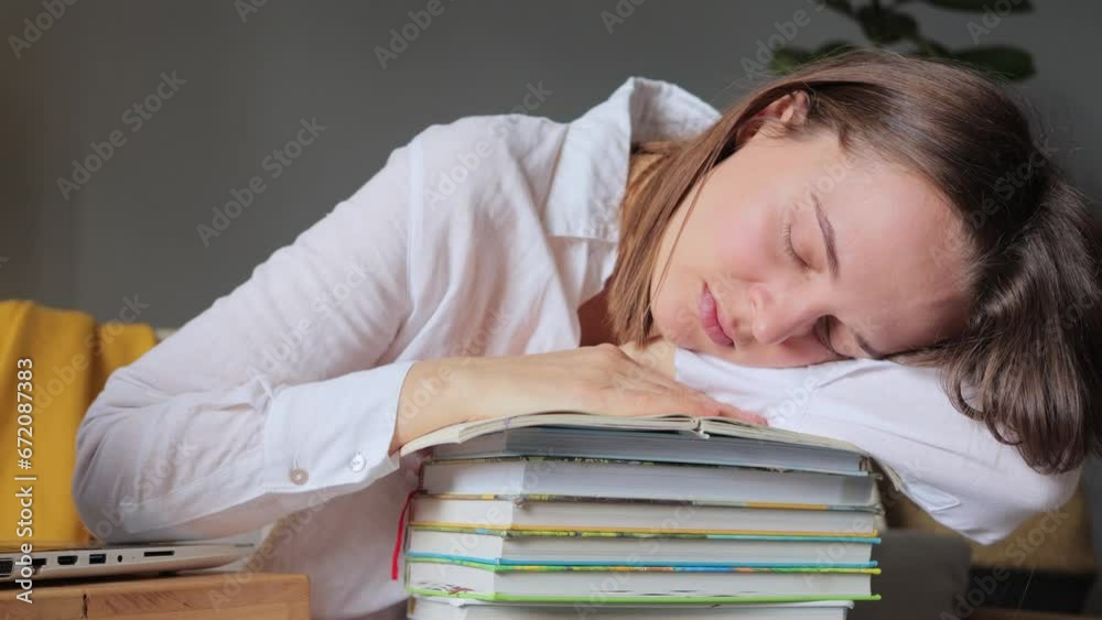 Young woman student with many books feeling fatigue after long hours studying sleeping on stack of books in home interior, falling asleep while preparing for test. Young woman student with many books feeling fatigue after long hours studying sleeping on stack of books in home interior, falling asleep while preparing for test.