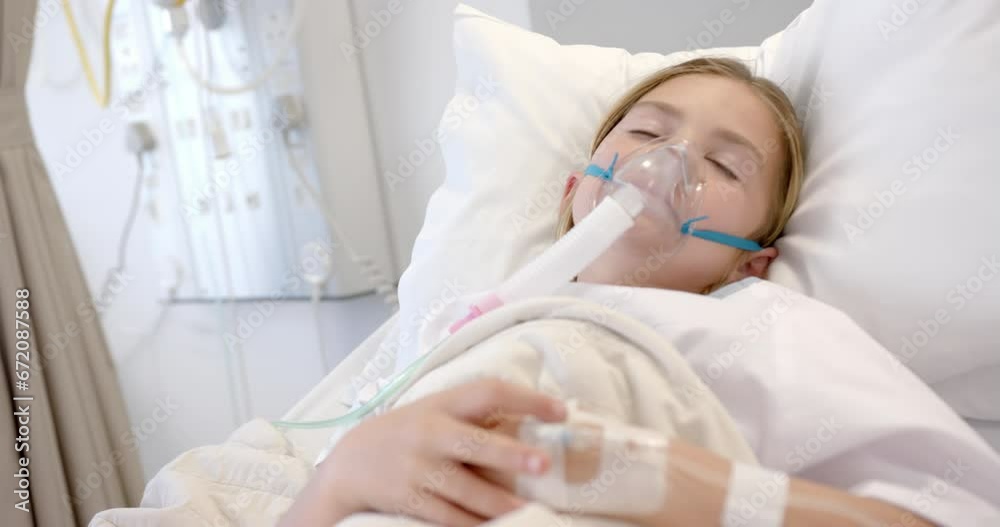Caucasian girl patient with oxygen mask and drip asleep in hospital bed, slow motion Caucasian girl patient with oxygen mask and drip asleep in hospital bed, slow motion