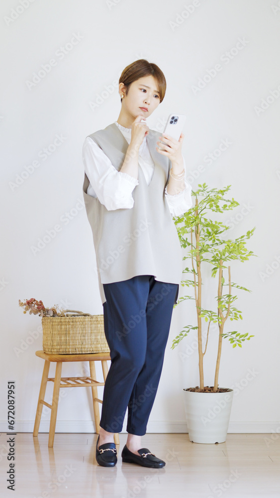 スマホを使う女性の全身（縦向き）