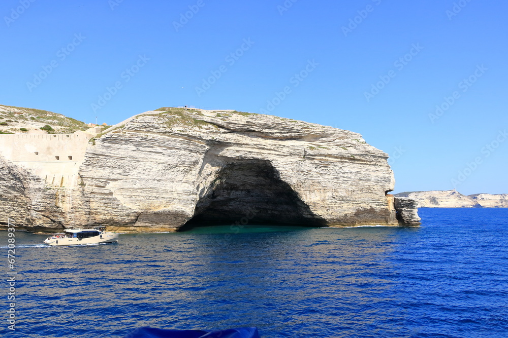 May 27 2023 - Bonifacio, Island of Corsica, France: boat in front of Grotto of Saint Antoine (Grotto of Napoleon) in Bonifacio