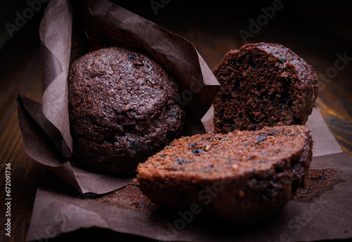 Whole and halved chocolate cupcake on a dark background. Muffin with chocolate chips on dark paper.