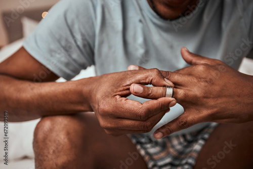 Divorce, breakup and wedding ring with hands of person in bedroom for fight, conflict and sad. Jewelry, doubt and affair with closeup of man and engagement band at home for angry, problem and loss photo