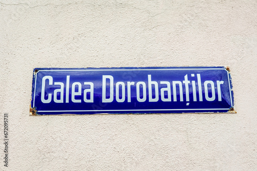 Beautiful vintage street sign showing Calea Dorobantilor (Dorobantilor Avenue) displayed on an street in the old city center of Bucharest, Romania, in a sunny day with clear blue sky © Cristina Ionescu