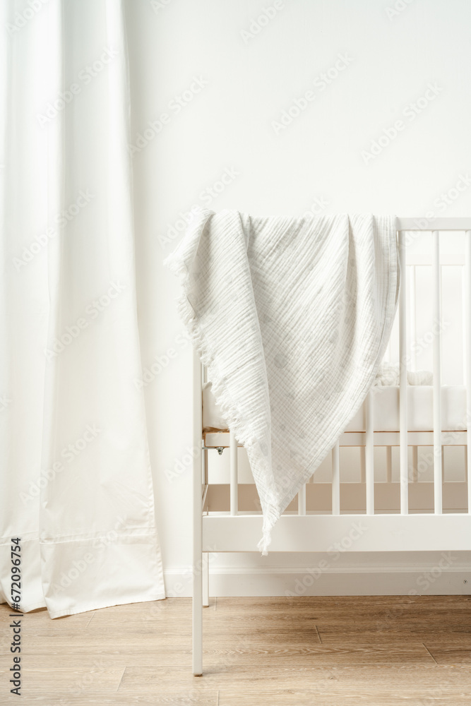 Muslin baby blanket hanging on child's bed in nursing room Muslin baby blanket hanging on child's bed in nursing room