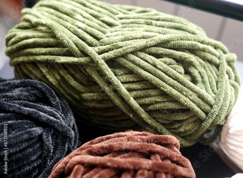 Photo of plush yarn skeins - green, black, and brown. Materials for crafts, knitting, crocheting.