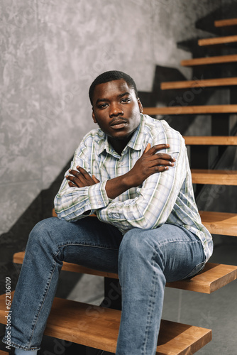 Young african man sitting on a wooden ladder in a room, portrait