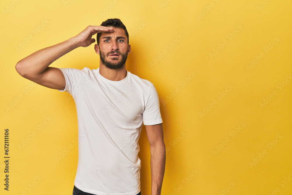 Young Hispanic man on yellow background shouts loud, keeps eyes opened and hands tense. Young Hispanic man on yellow background shouts loud, keeps eyes opened and hands tense.