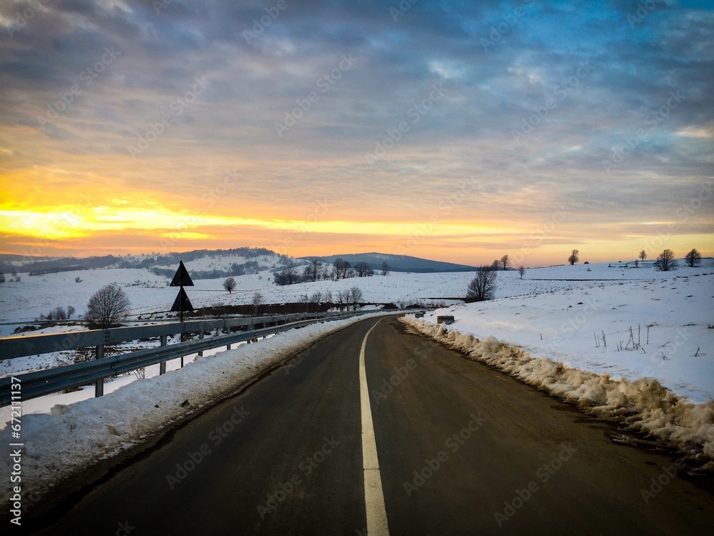 Sunset over empty road winding through the hills in winter