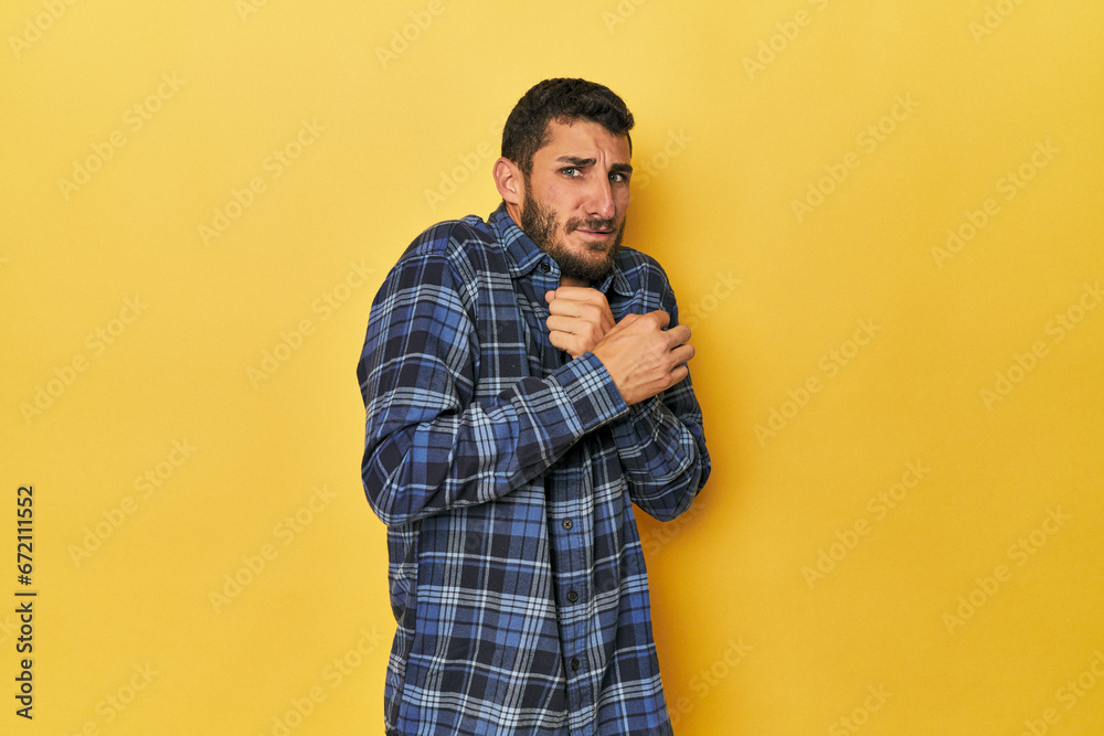 Young Hispanic man on yellow background scared and afraid. Young Hispanic man on yellow background scared and afraid.