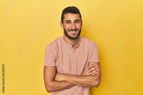 Young Hispanic man on yellow background laughing and having fun.