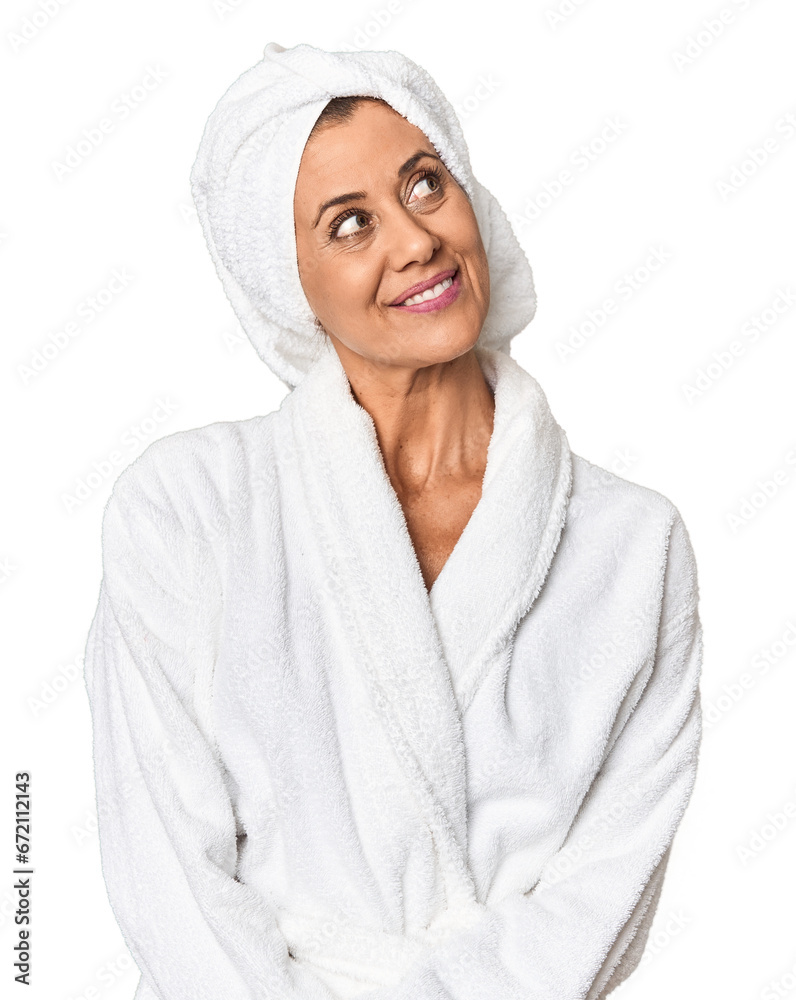 Obraz premium Middle-aged woman with towel post-shower in studio dreaming of achieving goals and purposes