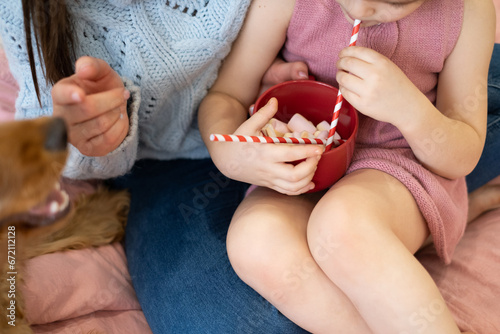 Mom and daughter hugging and drinking cocoa with marshmallows from a red cup