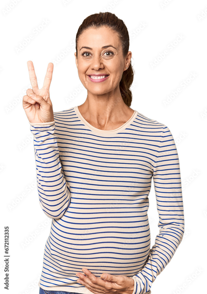 Pregnant middle-aged woman in studio setting showing number two with fingers. Pregnant middle-aged woman in studio setting showing number two with fingers.