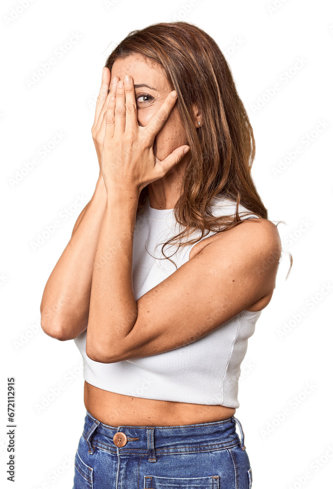 Middle-aged woman portrait in studio setting blink through fingers frightened and nervous. Middle-aged woman portrait in studio setting blink through fingers frightened and nervous.