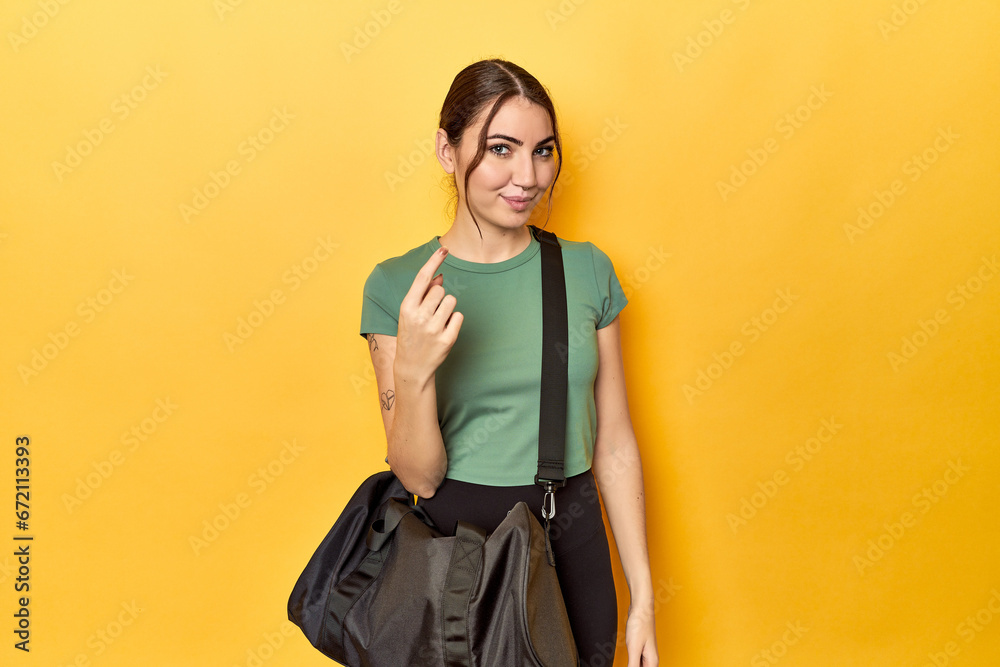 Athletic caucasian woman with sports backpack pointing with finger at you as if inviting come closer. Athletic caucasian woman with sports backpack pointing with finger at you as if inviting come closer.